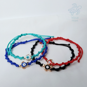 Foto de 4 manillas, con dije de tortugas cuyo caparazón es el ojo turco. Los colores de las manillas son azul rey, negro, rojo y turquesa.